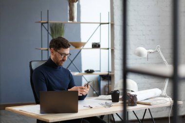 Genç adam akıllı telefon kullanıyor ve gülümsüyor. Mutlu iş adamı cep telefonu uygulamaları kullanıyor, mesaj atıyor, internette geziniyor, akıllı telefona bakıyor. Mobil aygıtlarla çalışan gençlerin kavramı