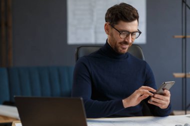 Genç adam akıllı telefon kullanıyor ve gülümsüyor. Mutlu iş adamı cep telefonu uygulamaları kullanıyor, mesaj atıyor, internette geziniyor, akıllı telefona bakıyor. Mobil aygıtlarla çalışan gençlerin kavramı