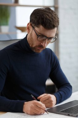 Ofiste planlarla çalışan bir mimar. Mühendis mimari planı inceliyor, bir inşaat projesi çiziyor. İş yerinde oturan sakallı yakışıklı bir adamın portresi. İş inşa kavramı