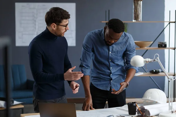 Equipo de ingenieros multirraciales trabajando en la oficina con impresiones azules y equipo de arquitecto bosquejando, discutiendo y planificando el proyecto de construcción. Socios disputando en el trabajo. Concepto de construcción empresarial — Foto de Stock