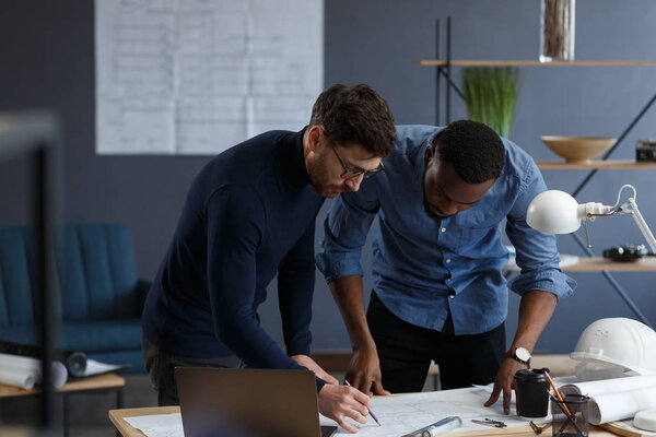 Multiracial engineer team working in office with blue prints and architect equipment sketching,discussing and planning construction project. Partners disputing at work. Business construction concept