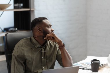 Ofiste projelerle çalışan Afro-Amerikalı bir mimar. Mühendis mimari planı inceliyor, bir inşaat projesi çiziyor. İş yerinde oturan siyah yakışıklı adamın portresi. İş konsepti