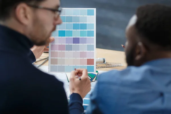 Multiraciale ingenieur team werken in het kantoor met kleurenpalet. Architecten selecteren kleuren voor het bouwen met behulp van kleurstalen, schetsen en planning bouwproject. Partners discussiëren op het werk — Stockfoto