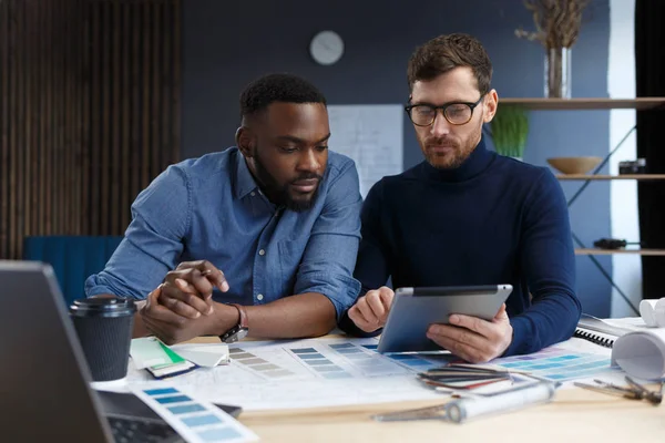 Equipo de ingenieros multirraciales trabajando en oficina con tablet PC. Los arquitectos seleccionan colores para la construcción utilizando muestras de color, bocetos y proyectos de construcción de planificación. Socios discutiendo en el trabajo — Foto de Stock