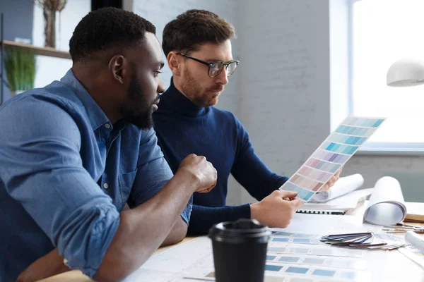 Equipo de ingenieros multirraciales trabajando en la oficina con paleta de colores. Los arquitectos seleccionan colores para la construcción utilizando muestras de color, bocetos y proyectos de construcción de planificación. Socios discutiendo en el trabajo — Foto de Stock