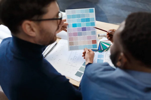 Multiraciale ingenieur team werken in het kantoor met kleurenpalet. Architecten selecteren kleuren voor het bouwen met behulp van kleurstalen, schetsen en planning bouwproject. Partners discussiëren op het werk — Stockfoto