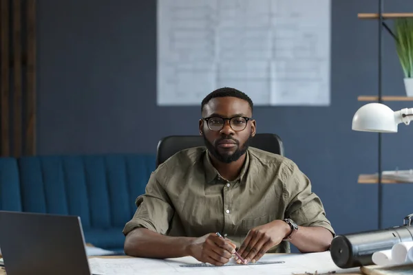 Arquitecto afroamericano que trabaja en la oficina con laptop.Business retrato de hombre barbudo guapo negro con anteojos sentados en el lugar de trabajo. empresario seguro se convirtió en éxito.Concepto de negocio — Foto de Stock