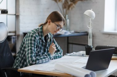Mimar ofiste planlar çiziyor. Mühendis bir inşaat projesi çiziyor. Mimari plan. İşine odaklanmış güzel bir kadının yakın plan portresi. İş inşa kavramı