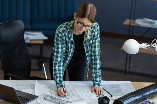 Arquitecto dibujando planos en la oficina. Ingeniero dibujando un proyecto de construcción. Plano arquitectónico. Retrato de cerca de una hermosa mujer concentrada en el trabajo. Concepto de construcción empresarial —  Fotos de Stock