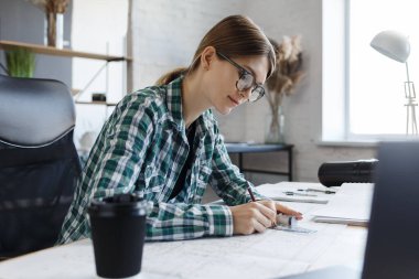 Mimar ofiste planlar çiziyor. Mühendis bir inşaat projesi çiziyor. Mimari plan. İşine odaklanmış güzel bir kadının yakın plan portresi. İş inşa kavramı