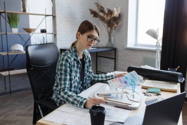 Renk paletinde çalışan kadın iç mimar. Renk örnekleri kullanarak, proje için yeni fikirler arayarak inşa etmek için renkleri seçin. İş yerinde güzel bir kadının portresi.