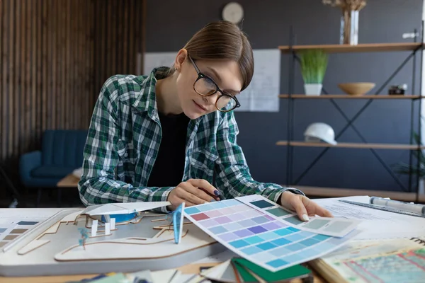 Vrouwelijke interieur ontwerper werkt in het kantoor met kleurenpalet. Architect selecteert kleuren voor het bouwen met behulp van kleurstalen, op zoek naar nieuwe ideeën voor het project. Portret van een mooie vrouw op het werk — Stockfoto