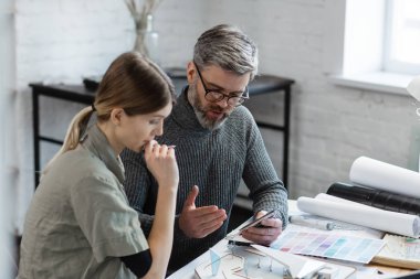 İç mimar takımı renk paletiyle ofiste çalışıyor. Mimarlar bina renklerini renk örnekleri, çizim ve inşaat projeleri kullanarak seçerler. İş yerinde tartışan ortaklar