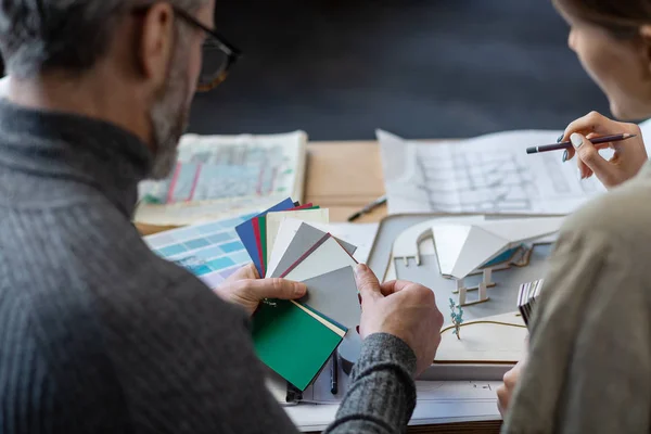 Interieur ontwerpers team werken in het kantoor met kleurenpalet. Architecten selecteren kleuren voor het bouwen met behulp van kleurstalen, schetsen en planning bouwproject. Partners discussiëren op het werk — Stockfoto