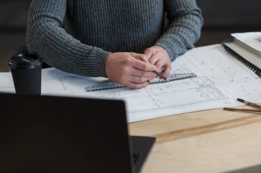 Ofiste planlarla çalışan iç mimar. Mühendis mimari planı inceliyor, bir inşaat projesi çiziyor. İş yerinde sakallı yakışıklı bir adamın portresi. İş inşa kavramı