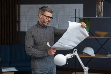 Ofiste planlarla çalışan bir mimar. Mühendis mimari planı inceliyor, bir inşaat projesi çiziyor. İş yerinde oturan sakallı yakışıklı bir adamın portresi. İş inşa kavramı