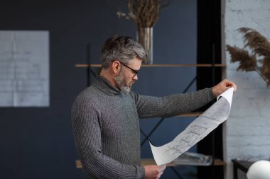 Ofiste planlarla çalışan bir mimar. Mühendis mimari planı inceliyor, bir inşaat projesi çiziyor. İş yerinde oturan sakallı yakışıklı bir adamın portresi. İş inşa kavramı