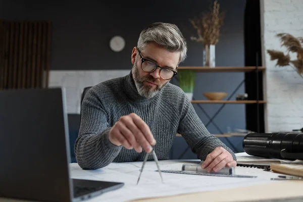 Diseñador de interiores que trabaja en la oficina con planos. Ingeniero inspeccionar plan arquitectónico, bosquejando un proyecto de construcción. Retrato de hombre barbudo guapo en el lugar de trabajo. Concepto de construcción empresarial — Foto de Stock