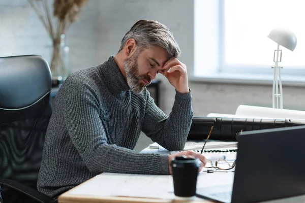 Zmęczony architekt pracujący po godzinach w biurze. Stresujący biznesmen ma problemy finansowe i szuka pomysłów na przezwyciężenie kryzysu finansowego. Przedsiębiorca w stanie upadłości. Koncepcja wypalenia i przepracowania — Zdjęcie stockowe