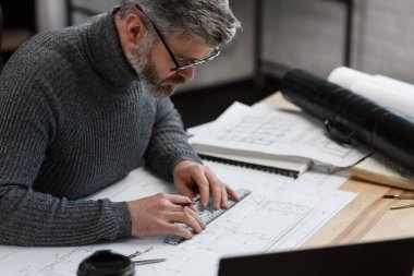 Mimar ofiste planlar çiziyor. Mühendis bir inşaat projesi çiziyor. Mimari plan. Yakışıklı sakallı adamın işine odaklanmış yakın plan portresi. İş inşa kavramı