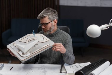 3D mimar, 3D model bir binada çalışıyor. Mühendis bina planını inceliyor, inşaat projesi için yeni fikirler arıyor. İş yerindeki yakışıklı sakallı adam. İş inşa kavramı