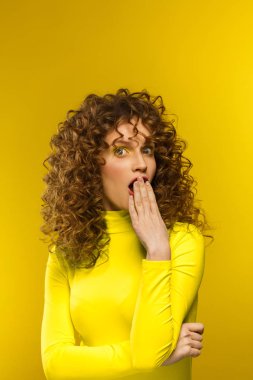 Wow. Reaction on unexpected news. Beautiful women with wide open eyes covering open mouth with hand, being surprised and shocked. Copy space,yellow background. Expressive faces. Body language concept