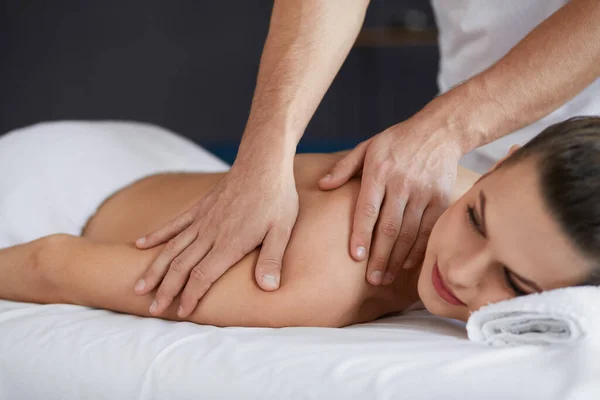 Junge schöne Frau genießt Rücken- und Shouders Massage in spa.professional Masseur behandelt eine Patientin in Wohnung.Entspannung, Schönheit, Körper-und Gesichtsbehandlung Konzept.Home Massage — Stockfoto