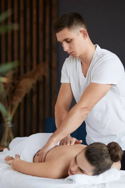 Młoda piękna kobieta korzystających z pleców i krzyczy masaż w spa.Professional masażysta leczy pacjentkę w apartamencie.Relaks, piękno, ciało i leczenie twarzy koncept.Home masaż — Zdjęcie stockowe