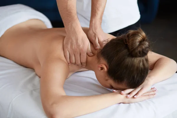 Młoda piękna kobieta ciesząca się szyi i krzyczy masaż w spa.Professional masażysta leczy pacjentkę w apartamencie.Relaks, piękno, ciało i leczenie twarzy koncept.Home masaż — Zdjęcie stockowe