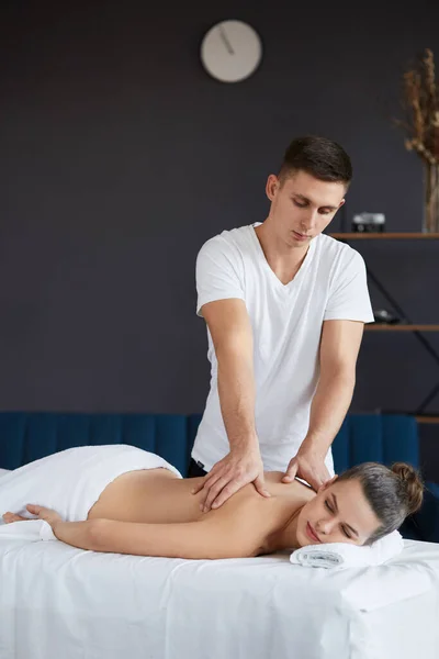 Jovem mulher bonita desfrutando de volta e shouders massagem em spa.Professional massagem terapeuta está tratando uma paciente do sexo feminino no apartamento.Relaxamento, beleza, corpo e rosto tratamento concept.Home massagem — Fotografia de Stock