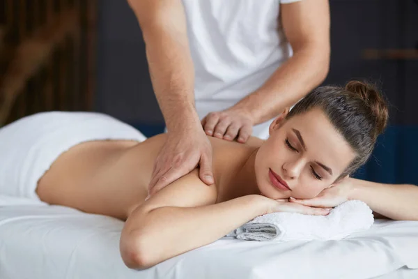 Junge schöne Frau genießt Rücken- und Shouders Massage in spa.professional Masseur behandelt eine Patientin in Wohnung.Entspannung, Schönheit, Körper-und Gesichtsbehandlung Konzept.Home Massage — Stockfoto