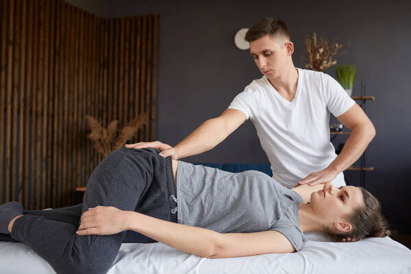 Female patient doing physical exercises with physiotherapist. Male therapist treating injured knee of young athlete.Post traumatic rehabilitation, sport physical therapy, recovery concept