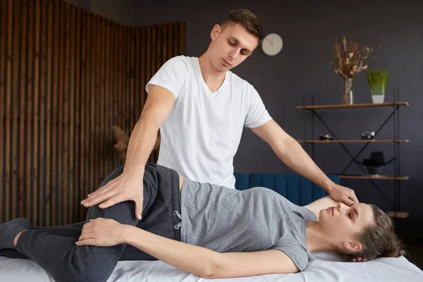 Female patient doing physical exercises with physiotherapist. Male therapist treating injured knee of young athlete.Post traumatic rehabilitation, sport physical therapy, recovery concept — Stock Photo, Image