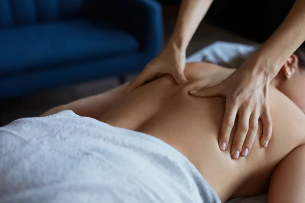 Giovane bella donna godendo schiena e grida massaggio in spa.Professional massaggiatore sta trattando una paziente in appartamento.Relax, bellezza, corpo e trattamento viso concettuale.Massaggio a casa — Foto Stock