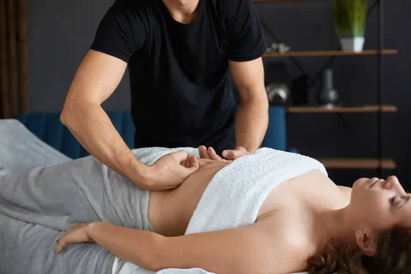 Молода красива жінка, насолоджуючись антицелюлітним масажем живота в спа. Професійний масажист лікує пацієнта жінки в квартирі.Релаксація, краса, концепція лікування тіла. Домашній масаж — стокове фото
