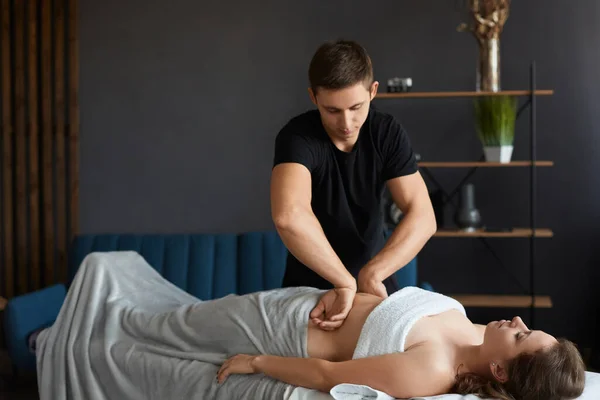 Młoda piękna kobieta korzystających z masażu brzucha antyklonowego w spa.Professional masażysta leczy pacjentkę w apartamencie.Relaks, piękno, leczenie ciała.Home masaż — Zdjęcie stockowe