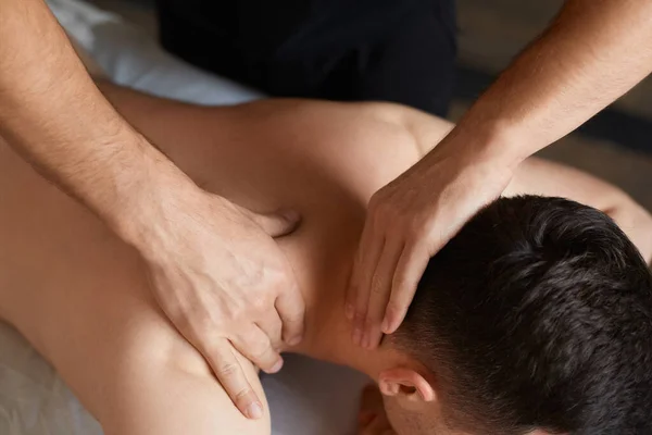 Ung man njuter av rygg och shouders massage i spa.Professionell massage terapeut behandlar en manlig patient i lägenhet.Avkoppling, skönhet, kropp och ansikte behandlingskoncept.Hem massage — Stockfoto