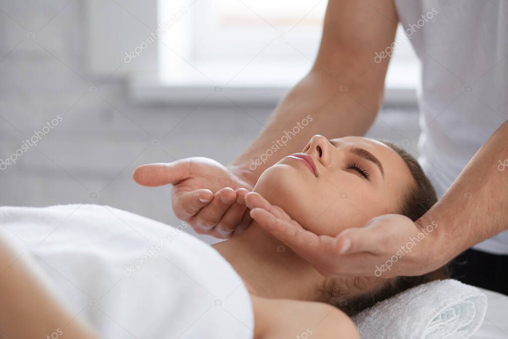 Young beautiful woman enjoying anti-aging facial massage.Male therapist making head massage to female client.Professional masseur.Relaxation,beauty,spa,body and face treatment concept