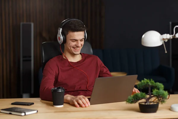 Young freelancer working in home office with laptop and listenin — Stock Photo, Image