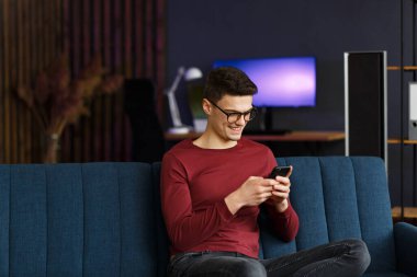 Genç serbest çalışan akıllı telefon kullanıyor ve gülümsüyor. Mutlu adam beni kullanıyor.