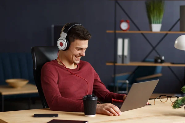 Young freelancer working in home office with laptop and listenin — Stock Photo, Image