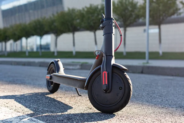 Gün batımında şehir manzarasında kaldırıma park edilmiş e-scooter 'ın yakın görüntüsü. Modern elektrikli scooter 'la son moda şehir ulaşımı. Çevre dostu hareketlilik kavramı — Stok fotoğraf