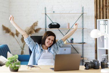 Evden çalışıyorum. Dizüstü bilgisayarla gülümseyen serbest kadın portresi. İş yerinde iyi sonuçlar aldıktan sonra rahatlama. Mobil aygıtlarla çalışan gençlerin kavramı