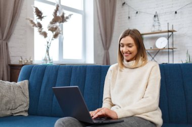 Evden çalışıyorum. Meslektaşlar ve serbest çalışanlarla çevrimiçi iletişim. Dizüstü bilgisayar kullanan ve gülümseyen genç bir kadın ressamın portresi. Mobil aygıtlarla çalışan gençlerin kavramı