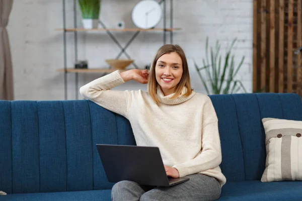 Trabajando desde casa.Comunicación en línea con colegas y freelancers.Retrato de una joven freelancer usando laptop y sonriendo. Concepto de jóvenes que trabajan con dispositivos móviles — Foto de Stock