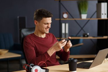 Genç adam ev telefonunda lapt ile oyun oynuyor.