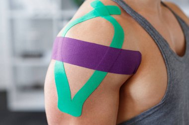 Kineziyoloji bandı. Hasta omzunda kineziyoloji bandı. Genç erkek atletin omuz tedavisi. Travma sonrası rehabilitasyon, spor fizyoterapisi, iyileşme konsepti