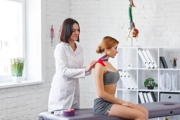 Kinesiologie-Aufnahmen. Physiotherapeut legt Kinesiologie-Klebeband an den Hals des Patienten. Therapeut behandelt verletzte Trapezmuskeln junger Sportler. Posttraumatische Rehabilitation, Sportphysikalische Therapie — Stockfoto