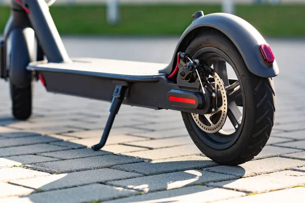 Nahaufnahme eines auf dem Bürgersteig geparkten E-Scooters im Stadtbild bei Sonnenuntergang. trendige Stadtverkehr auf modernen Elektroroller. Umweltfreundliches Mobilitätskonzept — Stockfoto