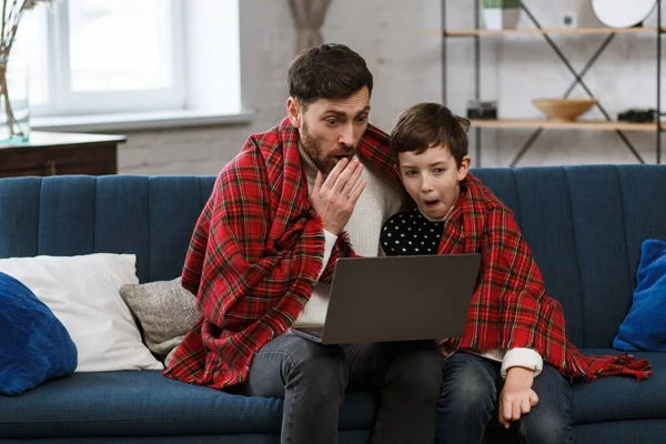 Quédate en casa. Retrato de padre e hijo sonrientes usando un portátil para una reunión en línea, videollamada, videoconferencia con familiares, educación en el hogar. Feliz familia pasando tiempo juntos en casa — Foto de Stock